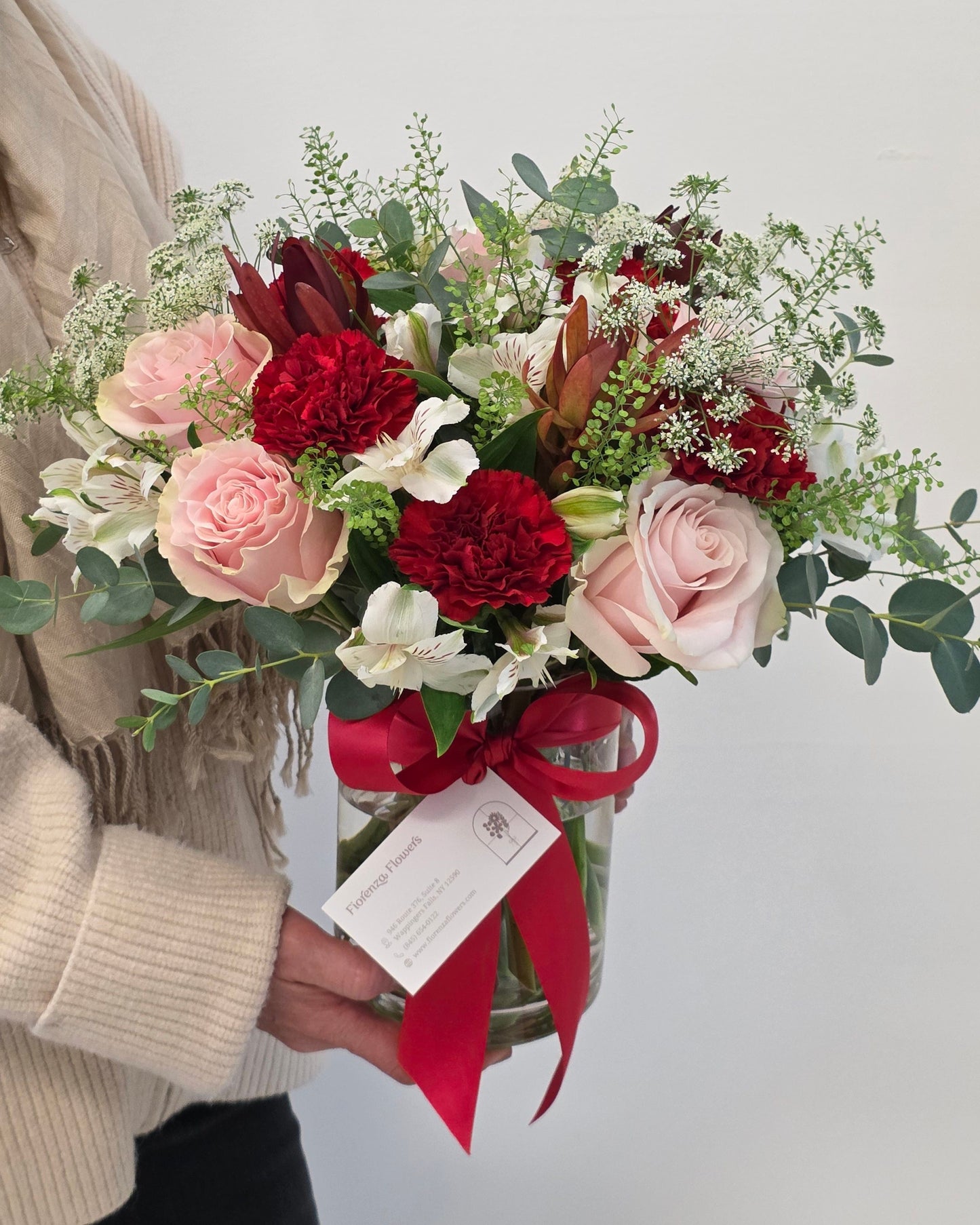 Photo of a woman holding a "Designer's Choice - Valentine's Edition" arrangement