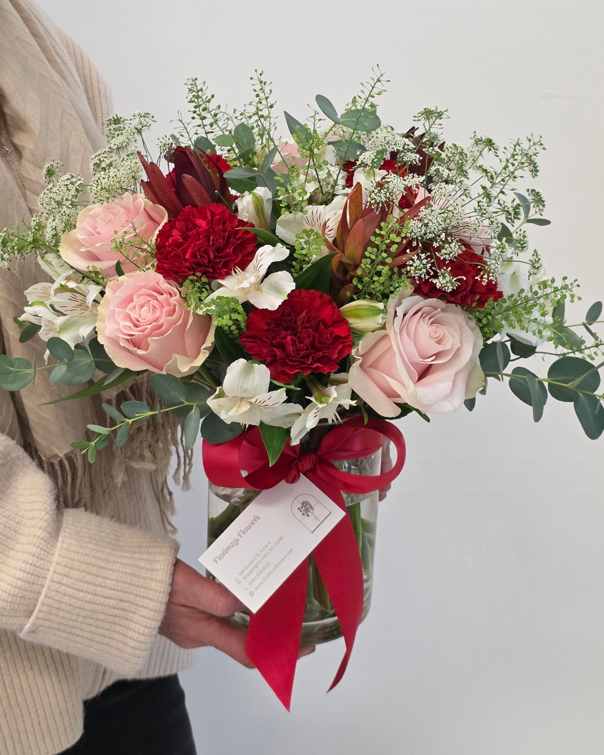 Photo of a woman holding a "Designer's Choice - Valentine's Edition" arrangement