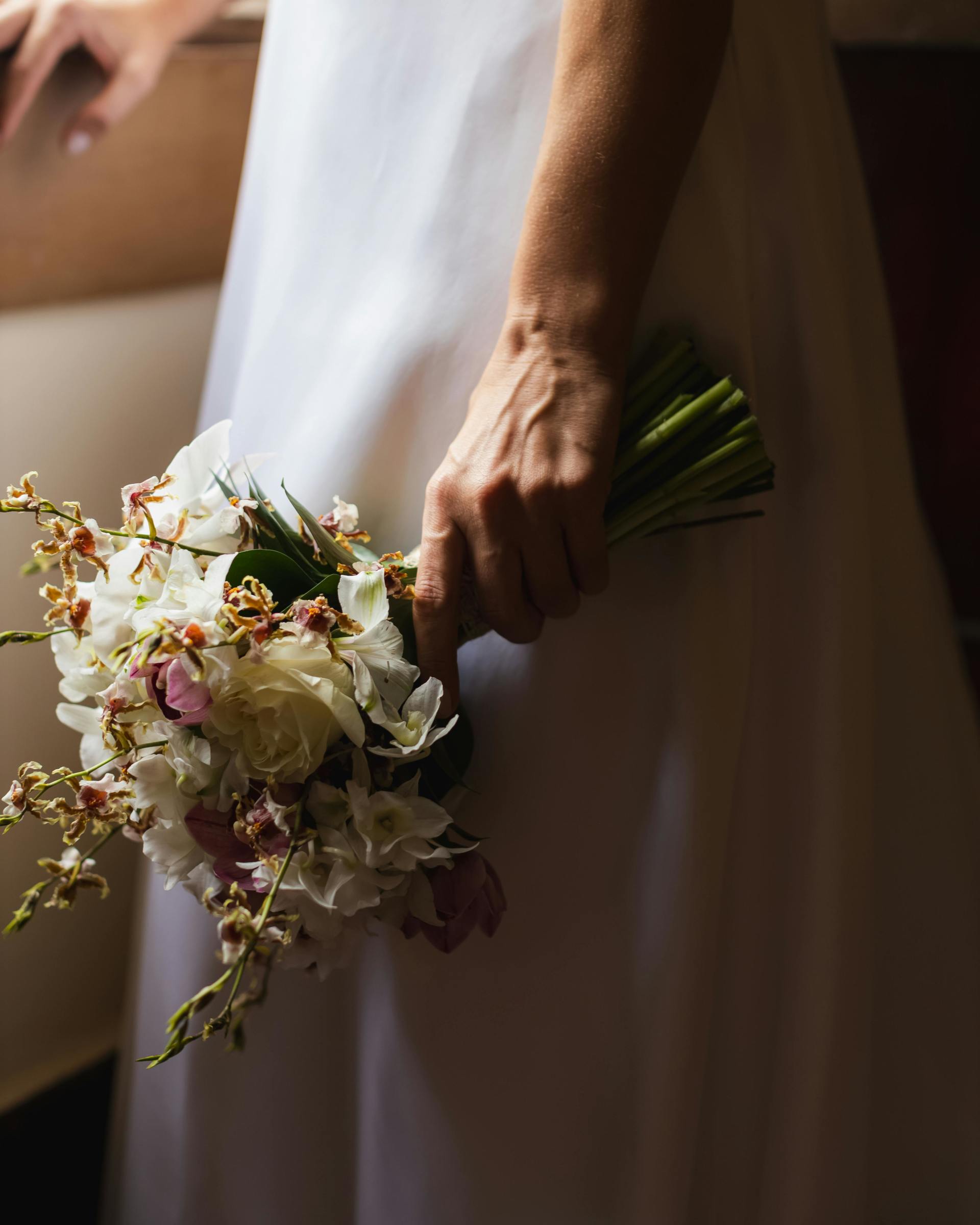 Photo of a woman holding a wedding bouquet and looking out a window - Services - Weddings